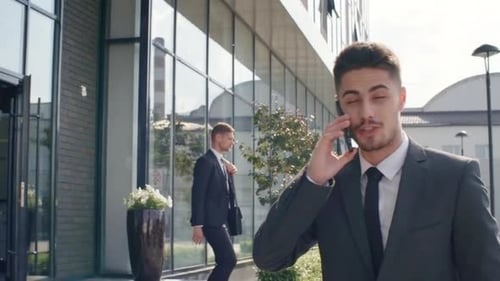 Young Businessman Walking and Talking on Phone