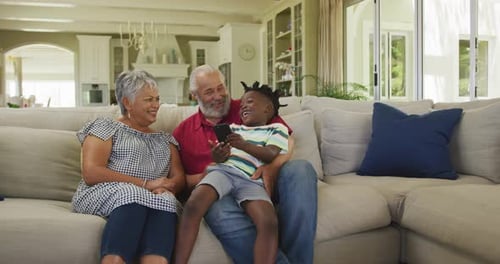 Boy Shows Device to Grandparents on Sofa