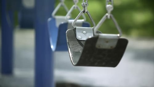 Slow motion of swings moving in the breeze.