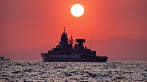 Warship sailing on the ocean at sunrise