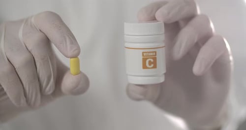 Hands Holding Pill and Medicine Bottle