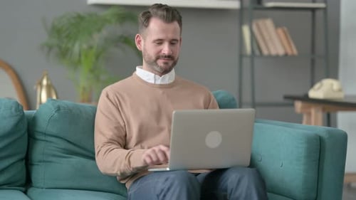 Adult Man Using Laptop on Turquoise Couch