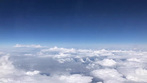 Stunning footage of aerial view above clouds from airplane window with blue sky.