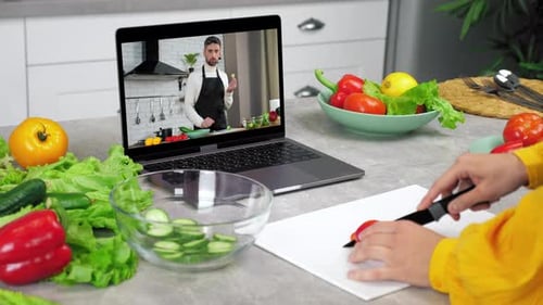 Un bloguero de comida en la pantalla de un portátil dice que enseña un curso de cocina a distancia para amas de casa