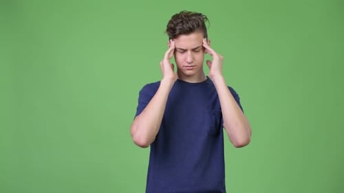 Young Man with Headache Stands Against Green Screen