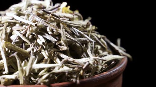 Trockene Teeblätter rotieren in einer Tonschale. Konzept - Traditioneller chinesischer Tee