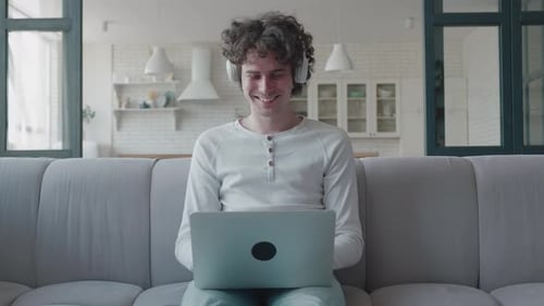 Young Adult Using Laptop and Headphones on Couch