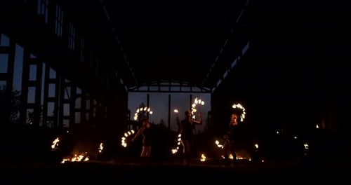 A Group of Professional Artists with Fire Show the Show Juggling and Dancing with Fire in Slow