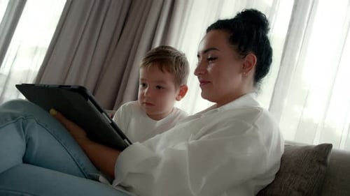 Woman and Child Viewing Tablet on Gray Couch