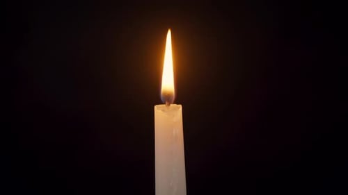 Nahaufnahme einer isolierten brennenden Kerze auf schwarzem Hintergrund