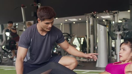 Trainer Guides Woman in Gym Workout