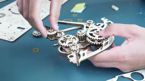 Jouet mécanique en bois Homme tenant dans les mains un petit puzzle en bois, assemblant un jouet