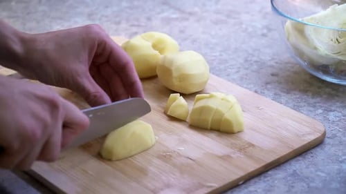 Nahaufnahme des Mädchens schneidet Kartoffeln auf einem Holzschneidebrett