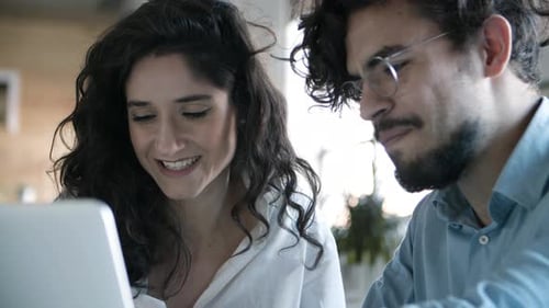 Team Discussing Tech on Laptop in Workplace