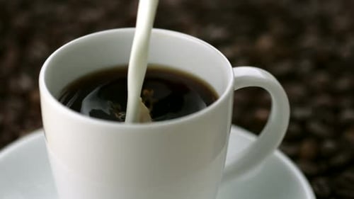 Cream Being Poured Into Fresh Cup of Coffee