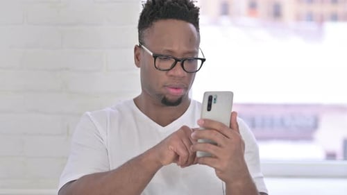 Portrait d'un homme africain décontracté à l'aide d'un smartphone