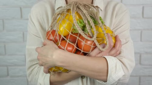Adult Holds Fresh Vegetables in String Bag