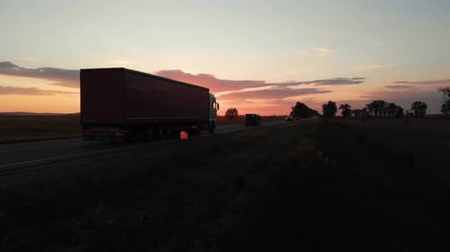 Aerial shot: flying along road with driving vehicles, trucks and cars