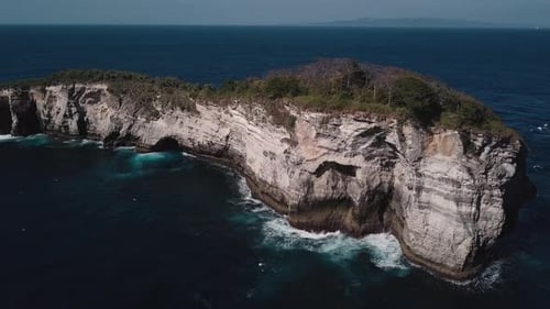 Aerial Shot of Waves Crashing on Small Tropical Rocky Island on the Coast