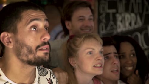 Football fans celebrating while watching televised match at sports bar together