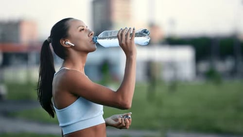 Woman Drinking Water After Exercise in City