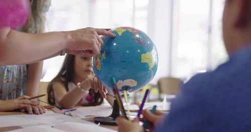 Female Teacher with Kids in Geography Class Looking at Globe