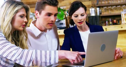 Young Adults Collaborate on Laptop in Urban Cafe