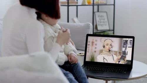 Back View of Mom Measuring the Temperature of a Sick Girl and Having Video Chat with Arab Woman