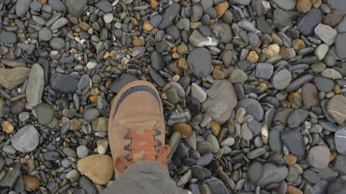 Man in Brown Sport Shoes Walks on Pebbles