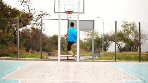 Back View of Young Man Playing Basketball and Throwing a Ball to the Basket Successfully