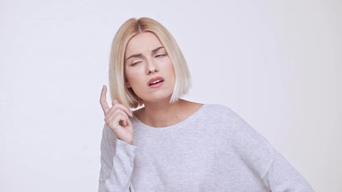 Junges schönes blondes Mädchen, das denkt, hat eine Idee vor weißem Hintergrund in Zeitlupe