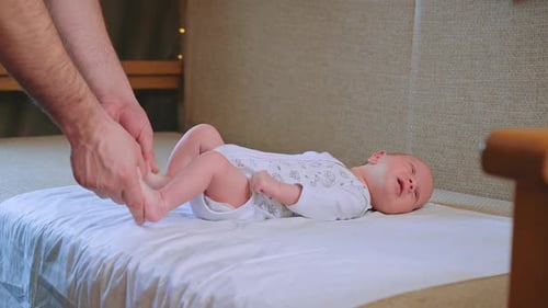 Father Exercising Legs of Lying Infant