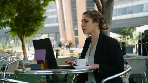 Junge Geschäftsfrau sitzt in einem Café und arbeitet an einem Laptop