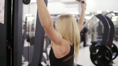 Atractiva joven rubia caucásica con un cuerpo deportivo que entrena duro en una máquina plegable plana en