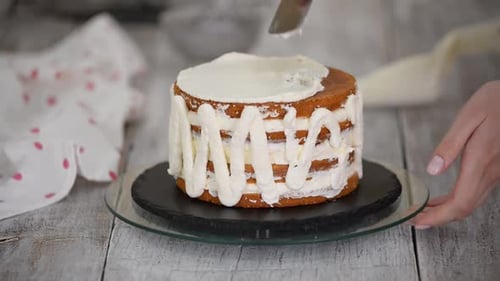 Confectioner Rotates the Cake on a Stand and Decorates with Cream From the Pastry Bag