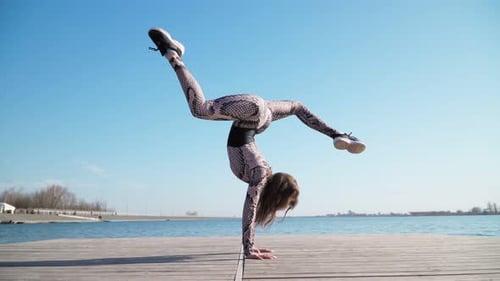 Joven gimnasta atlética se pone de pie en el pontón cerca de Blue Lake. Cámara lenta.