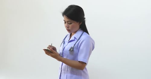 Woman in Medical Uniform Writing on Mobile Phone
