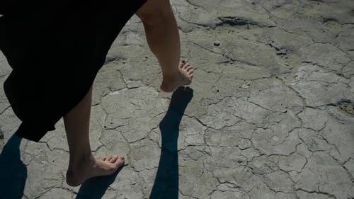 Barefoot Young Adult Walks Across Cracked Desert