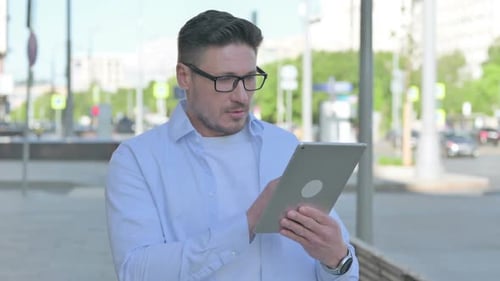 Man Uses Tablet Outside Building During Daytime