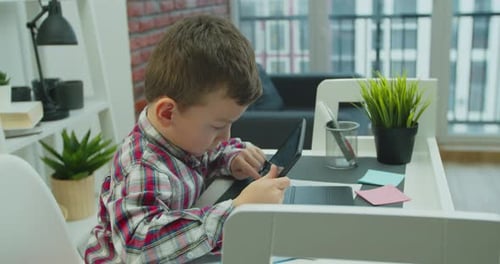 Boy Using Tablet Device at Home Desk