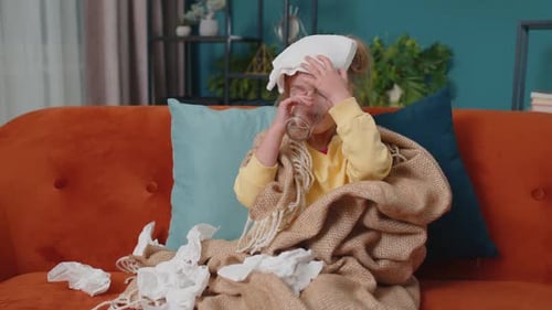 Sick Child Drinks Water on Couch At Home