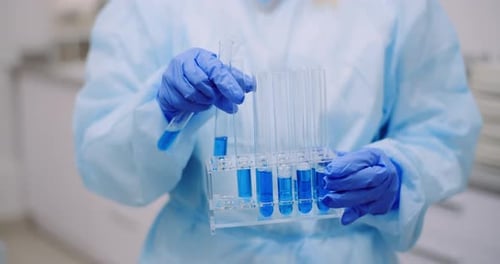 Scientist Inspecting Blue Liquid in Test Tubes