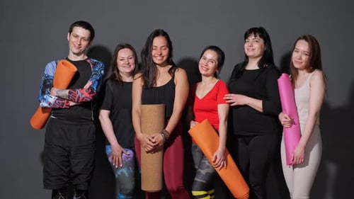 Smiling Fitness Group Poses with Yoga Mats