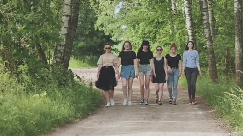 Um grupo de meninas está andando de mãos dadas fora da cidade