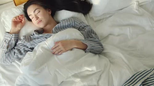 Top View of Cute Asian Student Sleeping in Comfortable Bed Lying Alone with Eyes Closed Enjoying