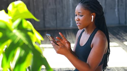 Woman Using Phone Wearing Earbuds Indoors