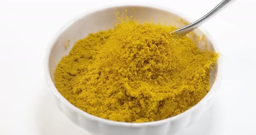 Curry Powder falling into a Bowl against White Background, Slow motion 4K