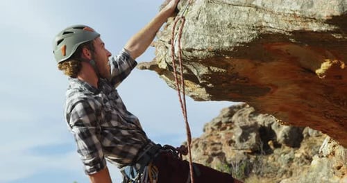 Mountaineer trying to climb up on the hill with the help of rope
