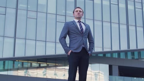 Man in Suit Buttons Jacket near Office Building