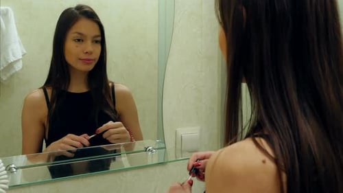 Portrait of Young Attractive Girl Rouging Her Lips and Smiling To Her Reflection
